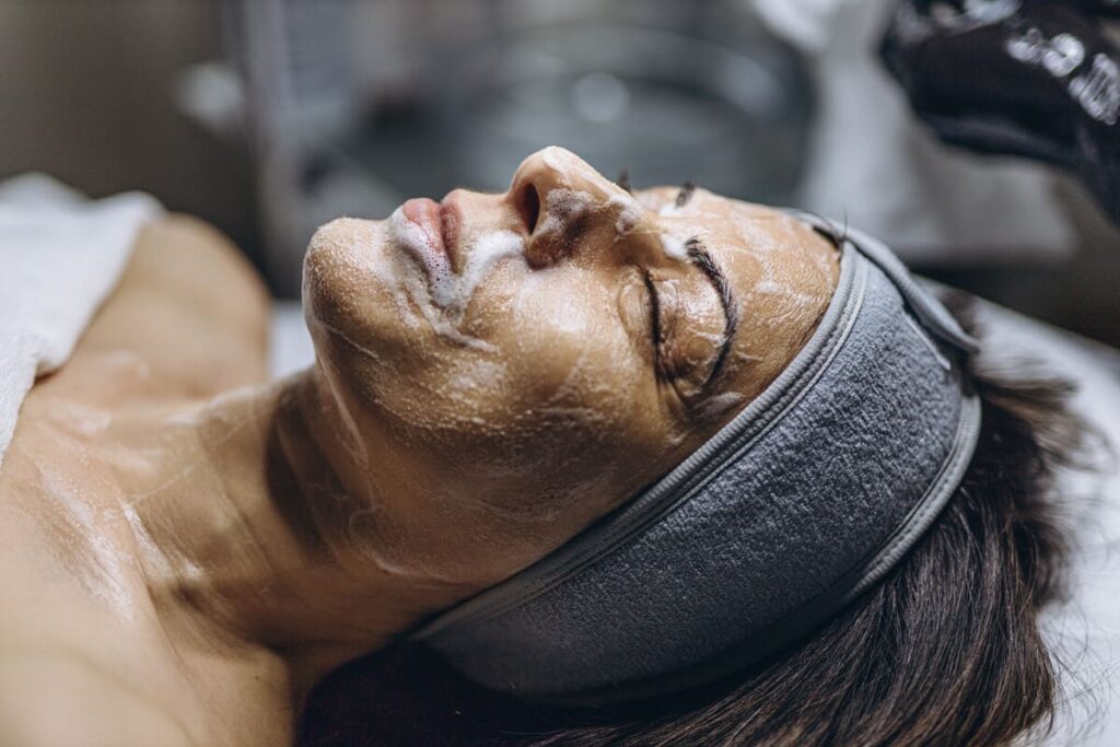 Mujer recibiendo tratamiento estético facial con aguas mineromedicinales en un spa.