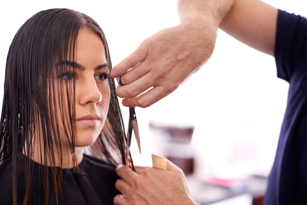 chica cortandose el pelo con un peluquero formado por inesbe
