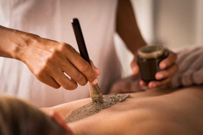 Aplicación profesional de peloides en estética en un tratamiento corporal purificante.