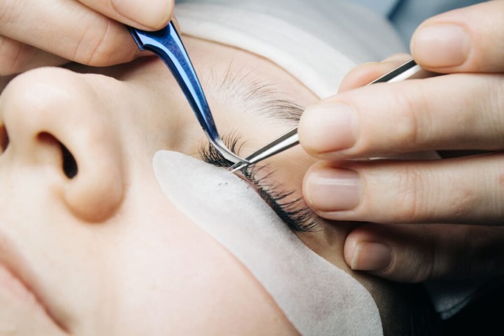 Primer plano de la aplicación de extensiones de pestañas como servicio complementario de belleza.